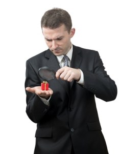 Businessman looking at a small present with a magnifying glass