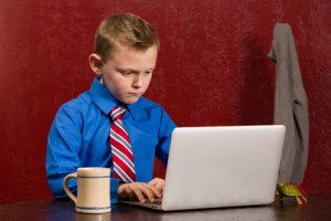 Young working boy with tie on computer